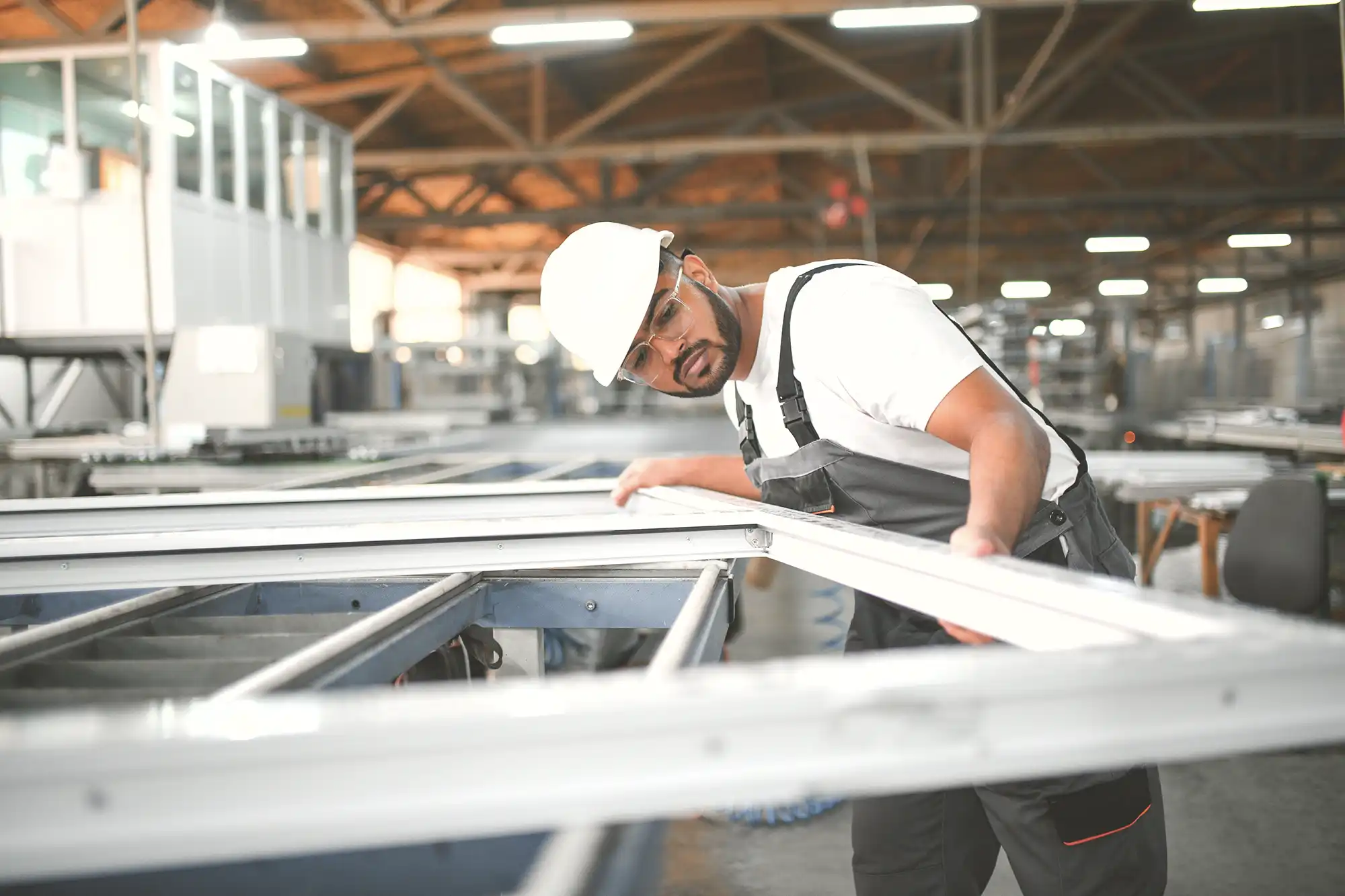 Worker in hard hat fitting components in a manufacturing plant.