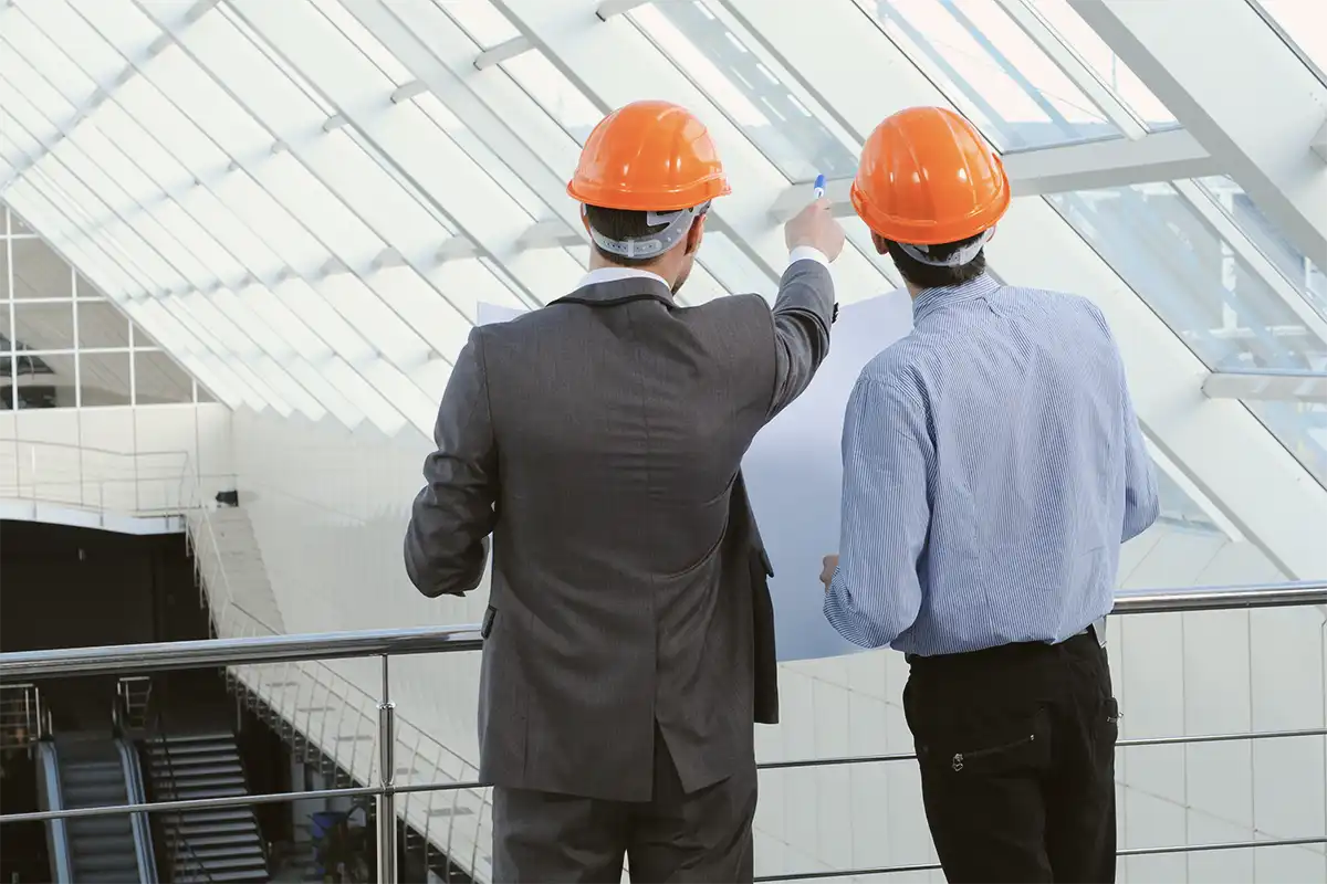 Businessmen in hard hats reviewing building details for risk assessment.