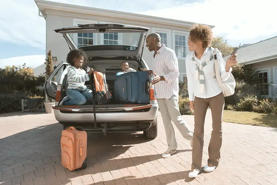 Family loading car in front of home for personal property insurance.