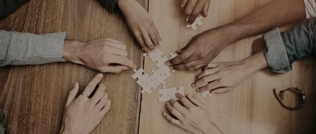 Overhead shot of team hands collaborating on a puzzle, symbolizing teamwork.
