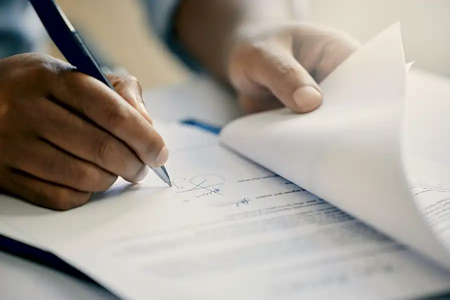 Close-up of hand signing document for specialized insurance solutions.