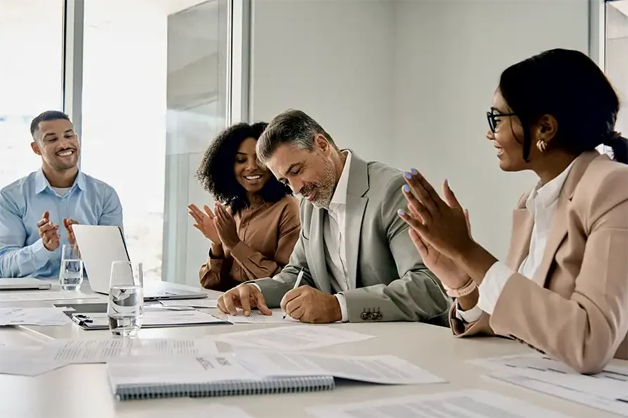 Deal closing with handshake and signatures, showing transaction risk coverage.